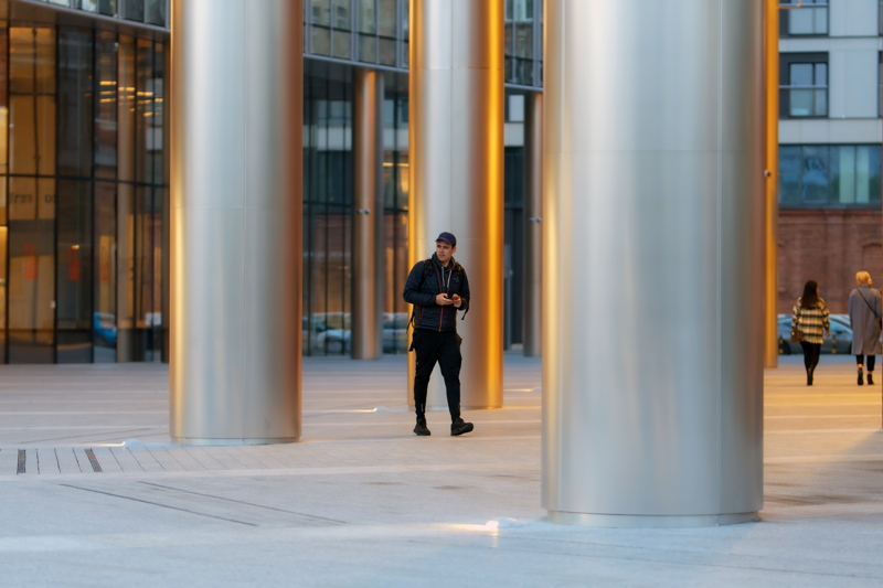 12 - A modern urban architectural scene with prominent, cylindrical metallic columns and expansive glass facades
